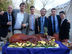 Fraternity alumni pose with roasted pig