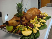 Fully "dressed" pig with fruit display, pineapple hat, and apple in mouth